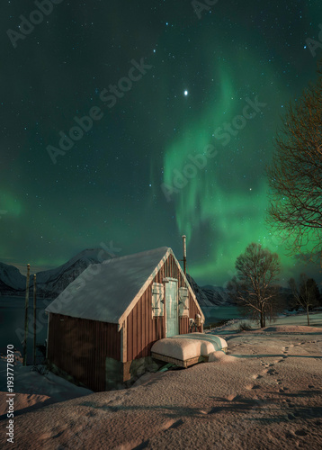 Casa de pescadores con aurora verde saliendo por la chimenea, paisaje artico en Noruega