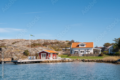 Coastal houses at Grönvik along Sotekanalen, Sote Canal, Bohuslän, west coast Sweden, with jetty, rocky shoreline and calm sheltered water
