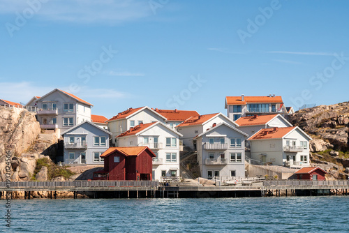 Waterfront apartment buildings at Hamnpromenaden, Kungshamn, Bohuslän, west coast Sweden, with red boathouses, wooden boardwalk and rocky shoreline