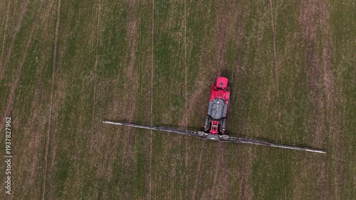 Aerial drone view of agricultural machinery spraying the field and working the land
