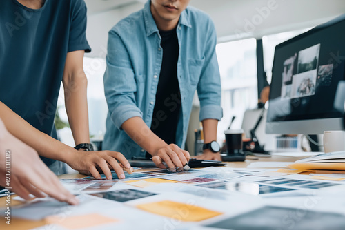 Professional creative agency studio displays colorful swatches and mood boards on wooden desk next to computer monitor showing photography project layouts.