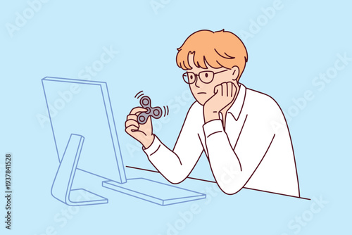 Boy with autism spectrum disorder using a fidget spinner to calm down and improve concentration while sitting at his desk for better focus and sensory regulation