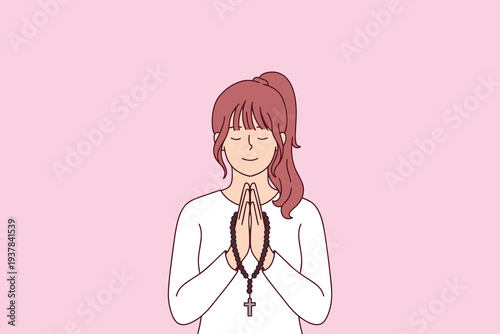 Young religious woman holding rosary beads and praying with closed eyes during Easter holy week to find spiritual peace and connect with her christian faith