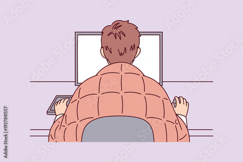 Tired man wrapped in a cozy blanket working at his computer late at night or feeling sick while staying productive from home during remote work hours