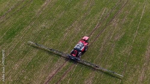 Aerial drone view of agricultural machinery spraying the field and working the land