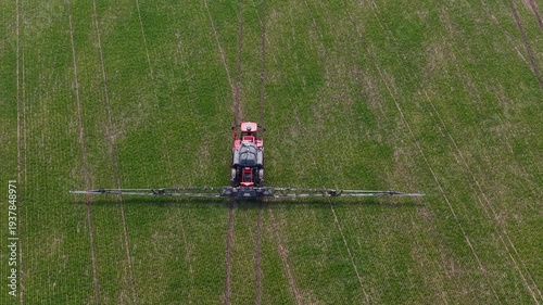 Aerial drone view of agricultural machinery spraying the field and working the land