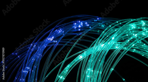 Blue and green glowing fiber optic cables arching on black background