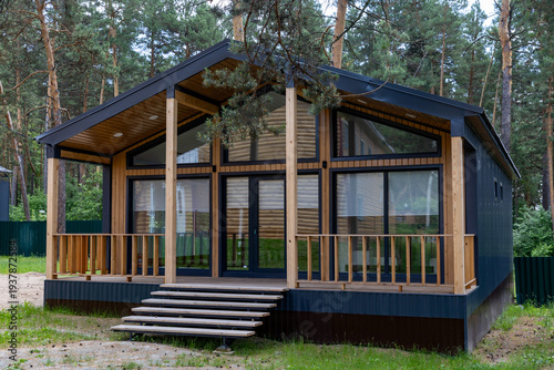 Vacation rental large wooden house in quiet pine forest, with terrace. Surrounded by tall trees, contemporary design with large glass windows.