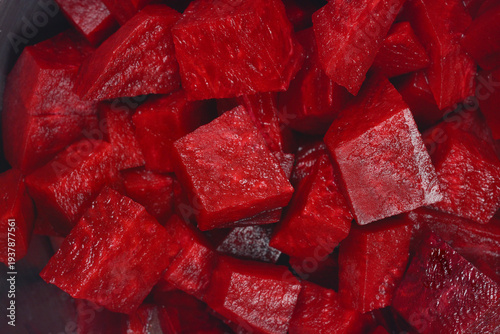 A detailed macro shot captures a dark, vibrant pile of raw, freshly diced beetroot cubes filling the entire frame