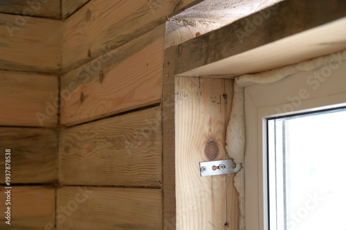 Installing a window in a wooden house opening. Window corner against a timber wall.