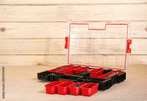 Construction site fastener organizer. Self-tapping screws in containers. toy house on wooden floor