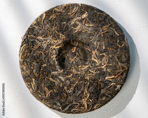 Photos Unique disc of pressed tea leaves on a plain surface surrounded by natural light