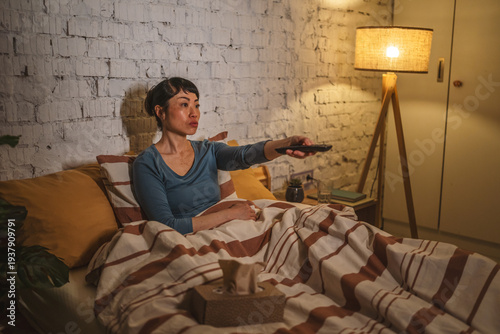 Foto Woman watching television in bed late at night