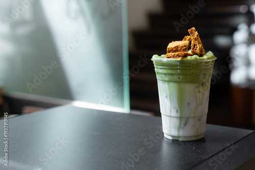 Iced matcha latte layered with milk and topped with crunchy brown sugar waffle pieces