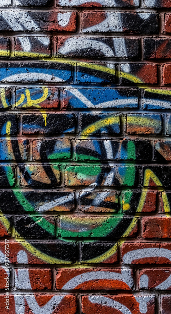 Fototapeta premium Brick wall covered with colorful graffiti, showing various shapes and colors, representing urban art and creative expression, vibrant and dynamic texture