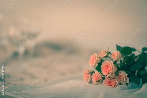 Soft pastel roses elegantly arranged on a cozy bed with champagne glasses in the background.