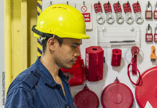 Safety control in maritime engineering as crew member operates lockout tagout board in ship engine department.