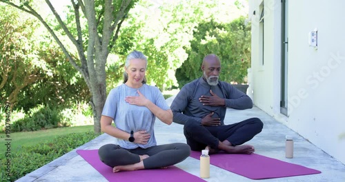 Senior couple settling into deep breathing, relaxing, hands on chest and belly on purple patio mats