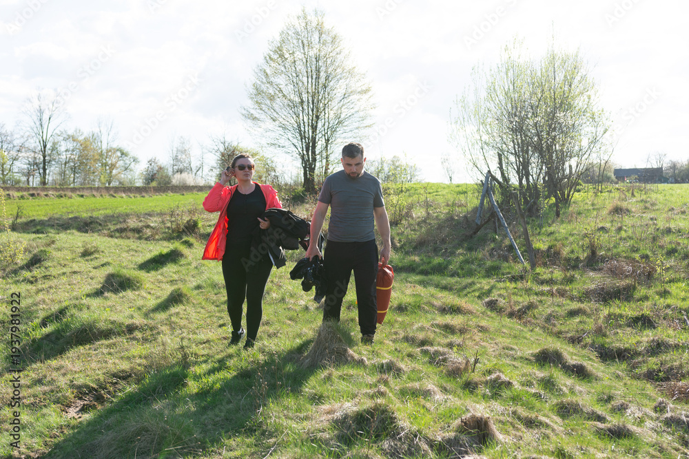 Fototapeta premium Volunteers restoring nature's beauty in a lush green field during a sunny afternoon, collecting trash and debris for a cleaner environment