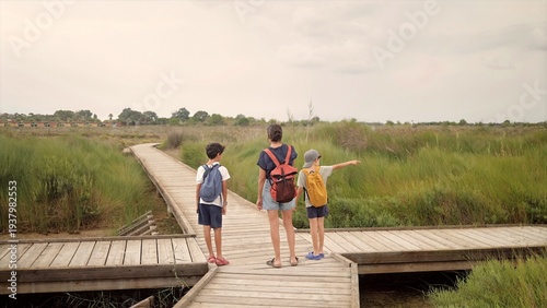 Photos Family with two children and mother hiking on a boardwalk path through green wet