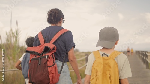 Fotografie Mother and children walking on a wooden boardwalk, exploring a nature reserve ne