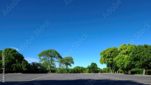 Empty parking lot under a bright blue sky with trees