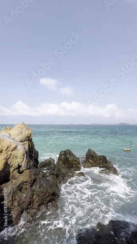 Waves crashing on rocky shore tropical beach nature scene clear skies seaside perspective serenity