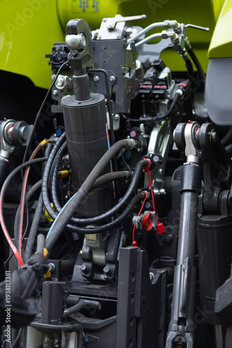 Close up of complex hydraulic system on a tractor hitch with cylinders, pistons and hoses. Powerful agricultural machinery detail for precise farm implement control and field work