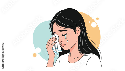 Emotional young woman with long dark hair crying and wiping away tears with a white tissue against a soft pastel background.