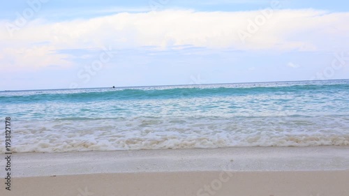 Tranquil seaside with smooth flowing waves, calm tropical beach under a pastel sky with gentle surf.
