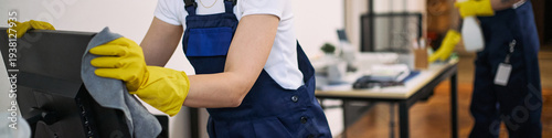 Fotografie Young adult Caucasian woman wearing yellow gloves cleaning computer monitor in m