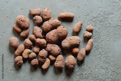 Obraz na plátne Close-up of a handful of textured red-brown clay pebbles on a gray grunge concrete floor