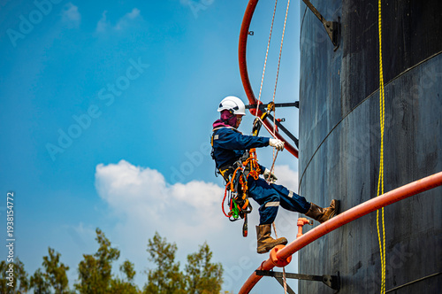 Male worker rope down access safety inspection of pipe fire water repair storage tank