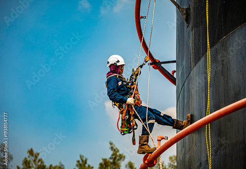 Male worker rope down access safety inspection of pipe fire water repair storage tank