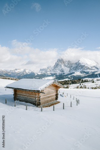 Blick von der Seiser Alm auf das Langkofelmassiv im Winter mit Hütten, Skipisten und Langlaufloipen im Vordergrund
