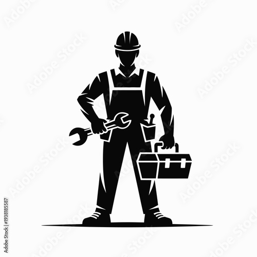 Mechanic holding wrench and toolbox standing confidently in uniform with hard hat