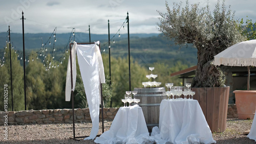 Elegant outdoor wedding reception setup with a champagne tower on a wine barrel and scenic mountain views