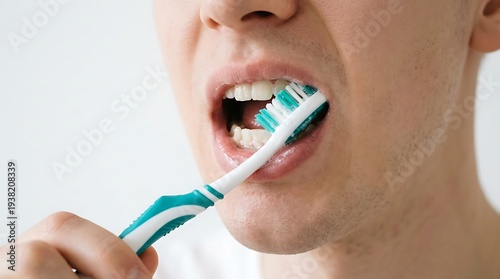 A man brushing his teeth with a toothbrush in a bathroom setting for oral hygiene.