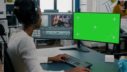 Bild auf Leinwand African woman videographer with headset processing film montage working at greenscreen, chroma key isolated display of computer