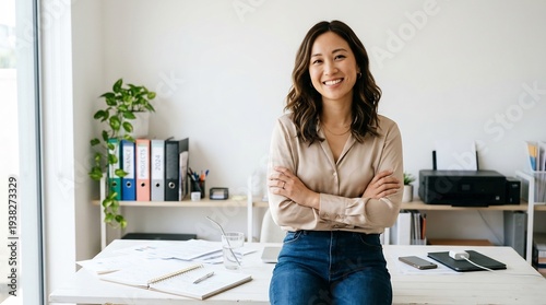 明るいオフィスで腕組み微笑む女性のポートレート写真