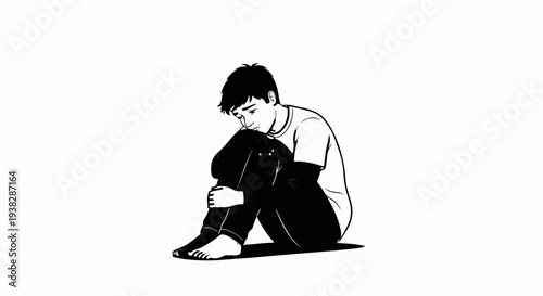 A young person sits huddled with knees to chest, looking down
