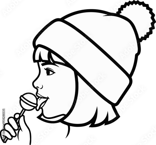 Child wearing a winter hat enjoys a lollipop, licking it