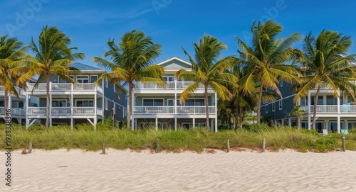 Beachfront three story residences with balconies and lush palm trees near sand
