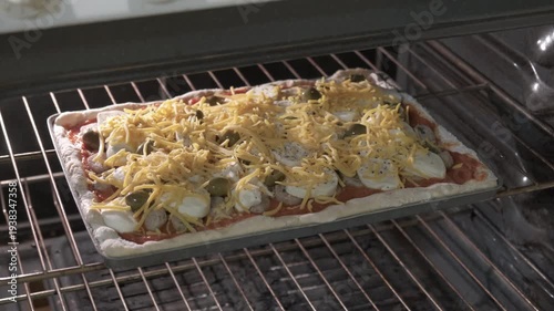 rectangular homemade pizza with tomato sauce and cheese ready to cook in the oven