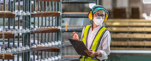 Cuadro en lienzo Textile inspection factory teamwork female supervisor in safety vest checking and discussing yarn production quality with woman worker in textile mill holding thread spool and clipboard