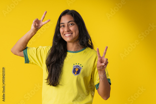 Happy Brazilian female soccer fan celebrating World Cup 2026 victory on yellow background.