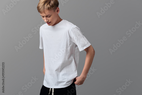 Fotografi Man in white t shirt standing against a minimalist gray backdrop, casual wear vi
