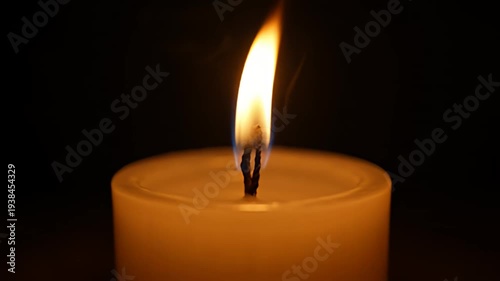 Close up of a lit candle flame glowing in a dark room