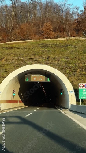 Car driving through road tunnel in Bosnia, illuminated interior with warm lights, empty highway creating motion, travel, transport and journey concept. Vertical footage