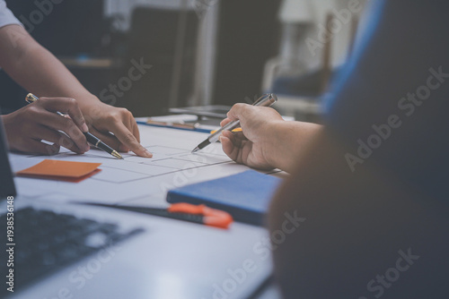 engineer and an architect reviewing blueprints and construction plans together at a bustling construction site